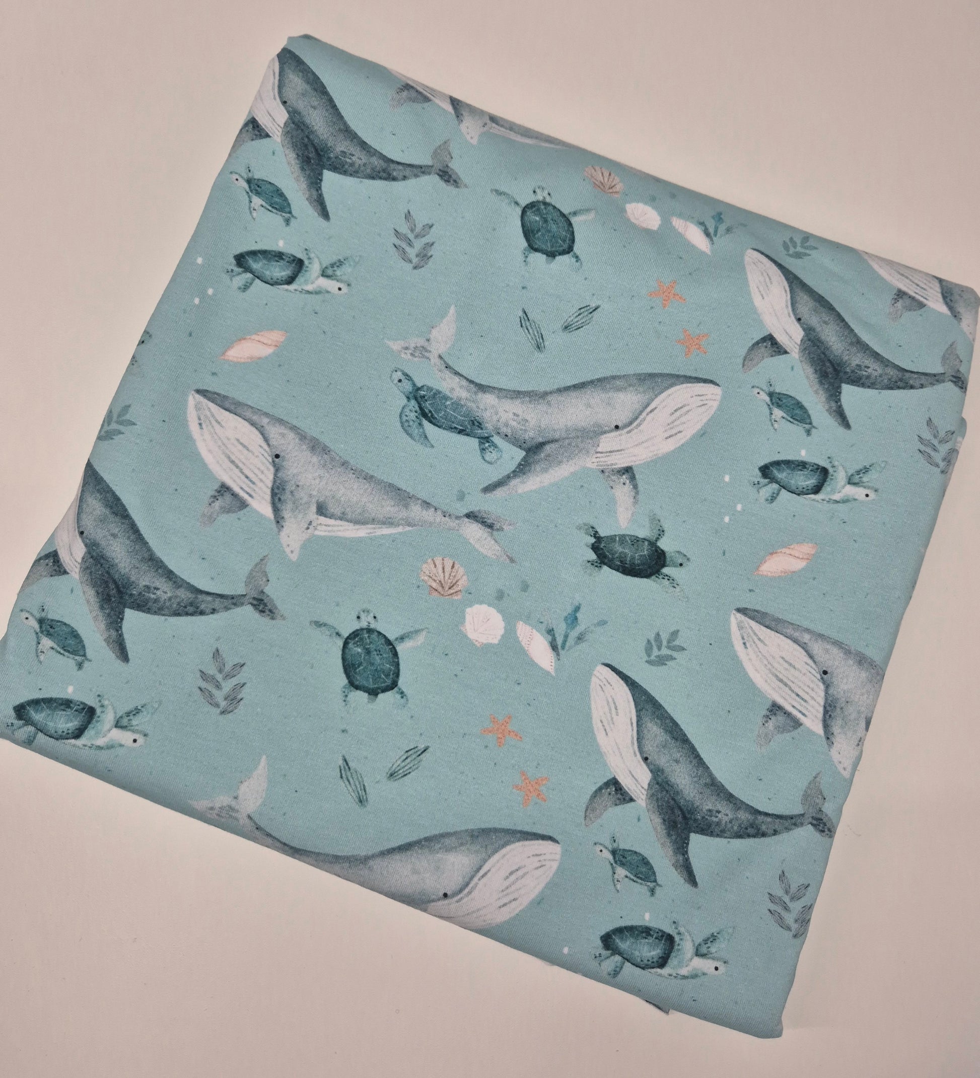 Fabric with whale and turtle pattern on a light blue background